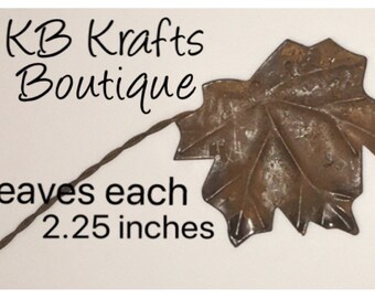 May include: A rustic metal leaf with a twisted wire stem. The leaf is approximately 2.25 inches in size and has a brown, weathered appearance. The text "KB Krafts Boutique" is at the top.
