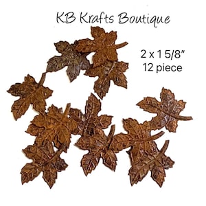 May include: A collection of twelve brown metal leaf embellishments, each measuring 2 x 1 5/8 inches. The leaves have a detailed, textured surface and are arranged on a white background. The text "KB Krafts Boutique" is visible.