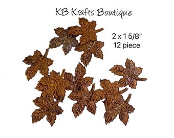May include: A collection of twelve brown metal leaf embellishments, each measuring 2 x 1 5/8 inches. The leaves have a detailed, textured surface and are arranged on a white background. The text "KB Krafts Boutique" is visible.