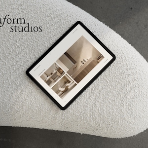 Puede incluir: Una tableta negra que muestra im&aacute;genes de dise&ntilde;o de interiores descansa sobre una superficie blanca texturizada. La pantalla de la tableta muestra un dise&ntilde;o de ba&ntilde;o moderno. Las palabras "nuform studios" est&aacute;n en la esquina superior izquierda.