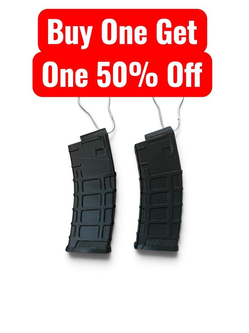 May include: Two black polymer rifle magazines with a textured grid pattern on the exterior surface. Each magazine features a metal wire hanger attached to the top. Above the magazines, a red rectangular sign displays the text Buy One Get One 50% Off.