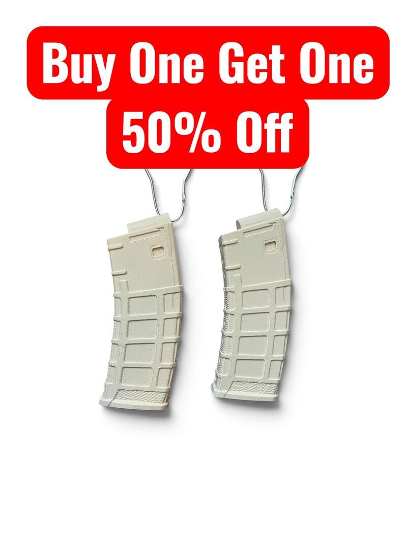 May include: Two off-white, curved rifle magazines with a textured grid pattern on the exterior, each suspended by a silver metal hook. Above the magazines, a red rectangular banner displays the white text: Buy One Get One 50% Off.