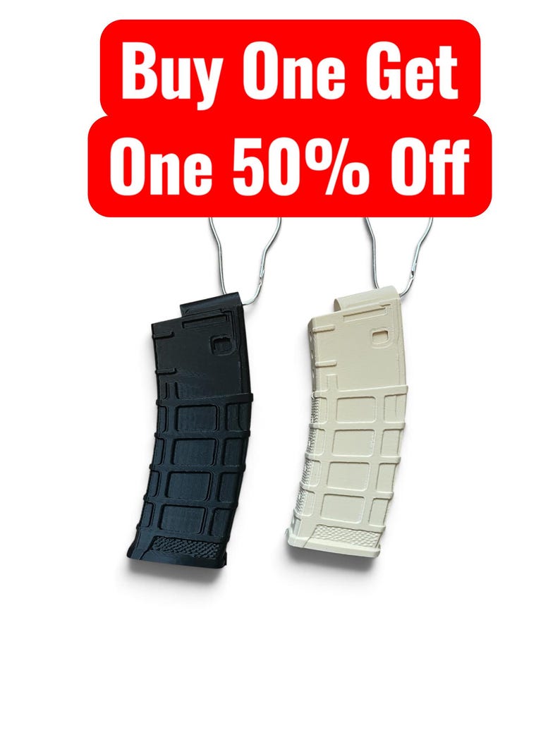 May include: Two curved firearm magazines, one black and one off-white, each hanging from a silver metal hook. Above the magazines is a red rectangular sign with white text that reads Buy One Get One 50% Off.