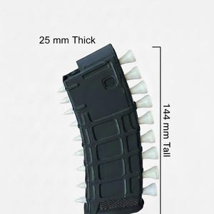 May include: A black magazine accessory with white spikes protruding from the sides. The object is labelled with dimensions of 25 mm thick, 144 mm tall, and 51 mm wide. The surface features a grid-like texture on the front and sides.