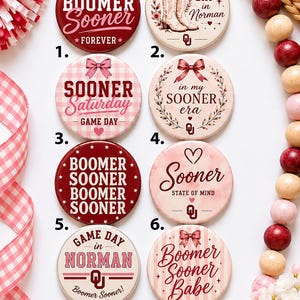 May include: A collection of ten circular pin-back buttons featuring various designs with the text Boomer Sooner, Game Day in Norman, Sooner Saturday, in my SOONER era, Sooner State of Mind, Boomer Sooner Babe, and the University of Oklahoma logo.