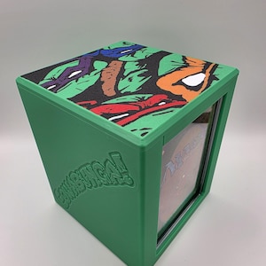 May include: A white ceramic mug with a black handle and the text "But First, Coffee" in a bold, black font. The mug is set against a blurred background, suggesting a cozy setting.