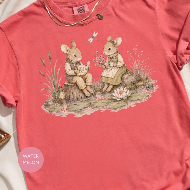 Two watercolor mice sit by a pond, one reading a book, the other holding flowers.
