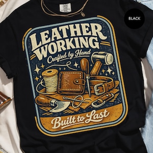 May include: Black t-shirt with a graphic design featuring leatherworking tools and the text "LEATHER WORKING Crafted by Hand Built to Last". The design includes a wallet, belt, and other tools.