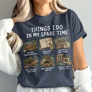 May include: A dark grey t-shirt featuring the text THINGS I DO IN MY SPARE TIME and six illustrated panels depicting reptile care activities, including cleaning terrariums, learning about reptiles, caring for scaly friends, feeding, building habitats, and relaxing.