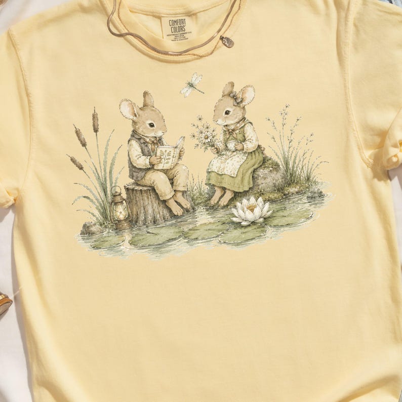 Two anthropomorphic bunnies by a pond with a book, tea, and a lantern.