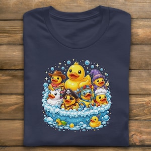 May include: Navy blue t-shirt with a colourful graphic of cartoon ducks in a bubble bath. The ducks are dressed in costumes such as a cowboy, pirate, and wizard. The design includes bubbles and stars.