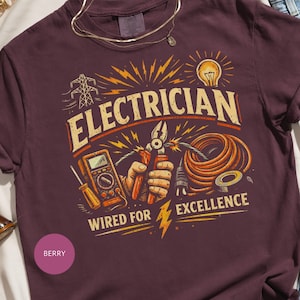 May include: Berry-colored t-shirt with a graphic design for electricians. The design includes the word "ELECTRICIAN" in a vintage font, along with tools, a lightbulb, and the text "WIRED FOR EXCELLENCE".
