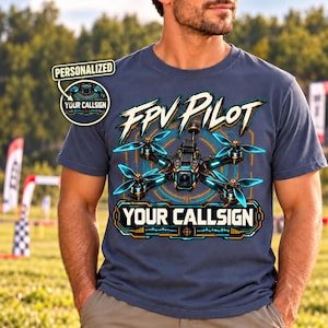 Peut inclure: Un t-shirt bleu ardoise à manches courtes avec un motif de drone FPV noir et orange, le texte FPV PILOT et YOUR CALLSIGN. Un badge circulaire en haut à gauche contient le texte PERSONALIZED YOUR CALLSIGN.