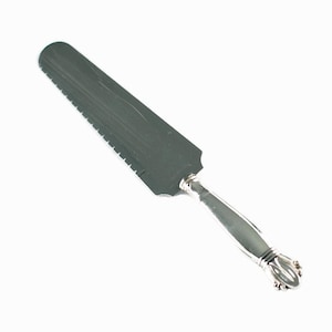 May include: A silver cake server with a serrated edge and a decorative handle.