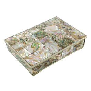 May include: A rectangular box featuring an exterior covered in iridescent abalone shell tiles. The lid and sides are composed of small, multi-shaped pieces of shell displaying shades of pink, green, and cream, all framed by a thin metal border.