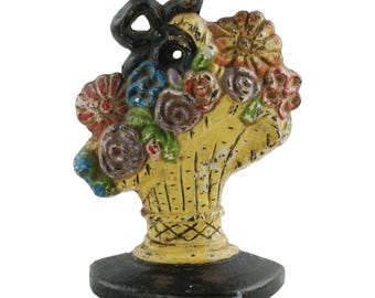Tope de puerta vintage de hierro fundido con flores variadas en cesta francesa y pintura retrorreflectante impregnada con microesferas de vidrio. Pieza de libro.