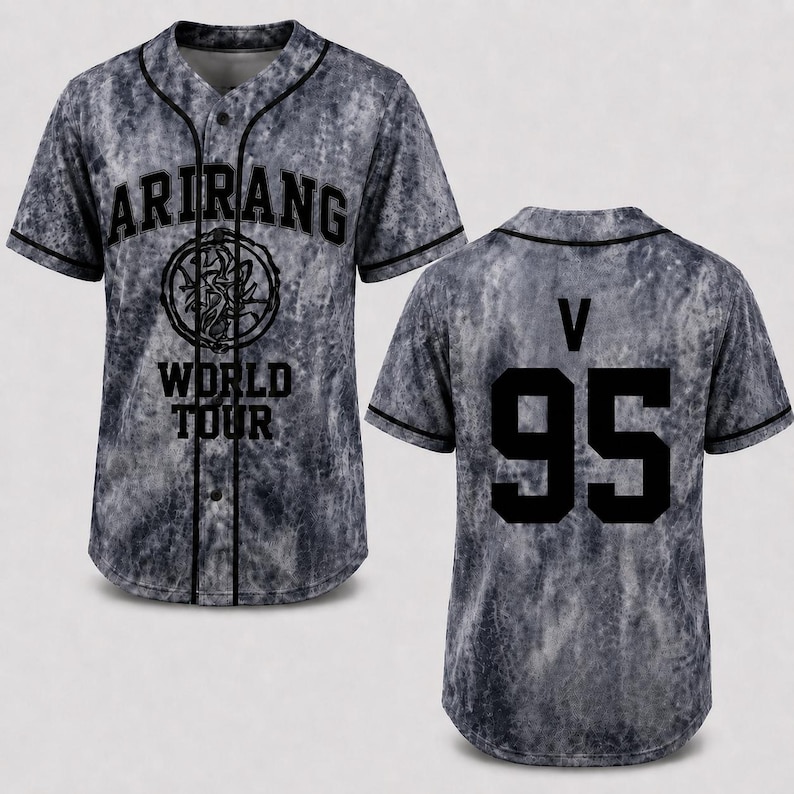 May include: Gray baseball jersey with black trim and buttons. The front features the word "ARIRANG" above a circular emblem and "WORLD TOUR" below. The back displays "V" above the number "95" in black.