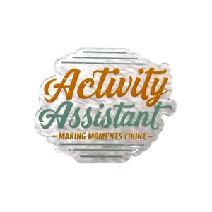 May include: A circular badge with a textured, pearlescent white background. The text Activity is in orange, Assistant is in sage green, and MAKING MOMENTS COUNT is in gold. Horizontal lines in sage green appear above and below the text.
