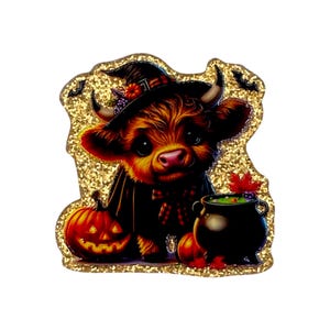 May include: A glittery sticker featuring a fluffy brown Highland cow wearing a black witch hat with a small pumpkin on top. The cow stands next to a carved jack-o'-lantern and a black cauldron filled with green liquid, accented by small bats.