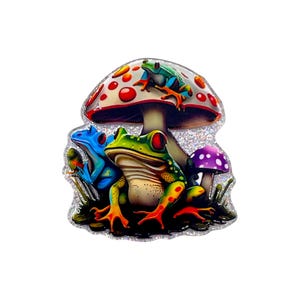 May include: A colorful pin featuring three frogs and two mushrooms. The frogs are in shades of blue, green, and teal, with red and orange accents. The mushrooms have red and purple caps with white spots, set against a glittery background.