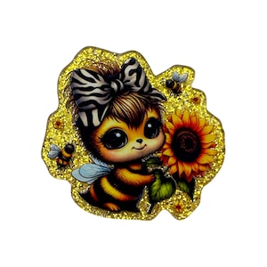 May include: A glittery yellow decorative cutout featuring a cartoon bee character with large eyes, wearing a black and white zebra-striped bow. The bee holds a bright yellow sunflower, surrounded by two smaller bees on a sparkling gold background.