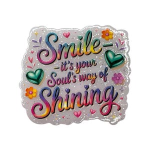 May include: A decorative sticker with the words "Smile - it's your Soul's way of Shining" in colorful script. The sticker features hearts, flowers, and glitter accents on a white background.