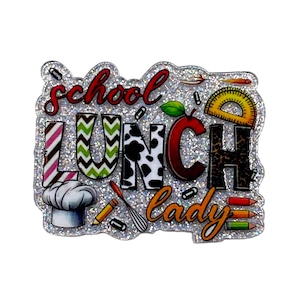 May include: A glittery, die-cut acrylic badge featuring the text "school LUNCH lady" in various patterns and colors. The design includes a chef hat, a red apple, a yellow protractor, a whisk, and colorful pencils on a sparkling silver background.