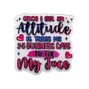 May include: A glittery, white sticker with the text "once I get an Attitude, it takes me 3-5 BUSINESS DAYS to fix My Face" in pink, blue, and black. The sticker has a heart and star design.