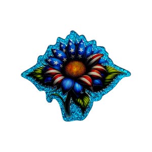 May include: A decorative sunflower with petals in red, white, and blue, resembling the American flag. The flower has a yellow center and is surrounded by a glittery blue border. Green leaves are visible at the base.
