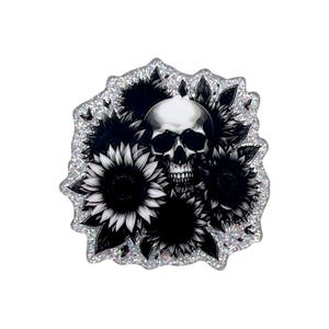 May include: A die-cut sticker featuring a central human skull surrounded by several black and white sunflowers with dark leaves. The entire design is set against a shimmering, holographic silver background with a jagged, irregular border edge.