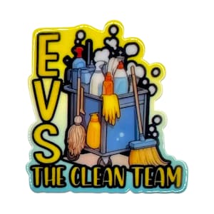 May include: A colorful pin featuring a cleaning cart with cleaning supplies, mops, and gloves. The pin has the text "EVS THE CLEAN TEAM" in yellow and blue. The pin is on a white background.