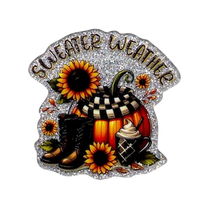 May include: A glittery sticker featuring the text SWEATER WEATHER in black letters. The design includes a bright orange pumpkin wrapped in a black and white checkered scarf, dark brown boots, yellow sunflowers, and a mug of coffee with whipped cream.