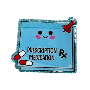 May include: A light blue, glitter-edged sticker in the shape of a sticky note. The note features the words "PRESCRIPTION MEDICATION" and a smiling face. Two red and white capsules and a red push pin are also shown.