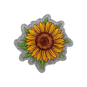 May include: A decorative sunflower with yellow petals, a brown center, and green leaves. The sunflower is outlined with a silver glitter border. The image is on a white background.