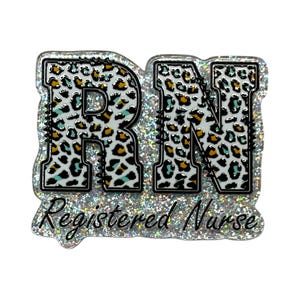 May include: A glittery RN badge with a leopard print design in the letters. The badge has a black outline and the words "Registered Nurse" are written in cursive below the letters. The leopard print includes white, black, teal, and gold.