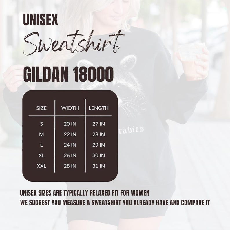 Puede incluir: Sudadera unisex negra con un gr&aacute;fico de mapache. La imagen incluye una tabla de tallas con medidas en cm: S (51 cm de ancho, 69 cm de largo), M (56 cm de ancho, 71 cm de largo), L (61 cm de ancho, 74 cm de largo), XL (66 cm de ancho, 76 cm de largo) y XXL (71 cm de ancho, 79 cm de largo).