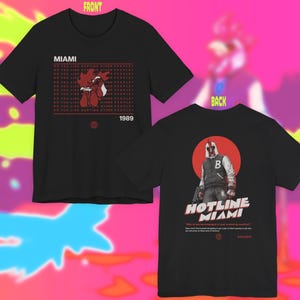 May include: Black t-shirts with graphic designs. The front shirt features a rooster illustration with the text "MIAMI" and "DO YOU LIKE HUNTING OTHER PEOPLE". The back shirt displays a figure in front of a red circle with "HOTLINE MIAMI" text.