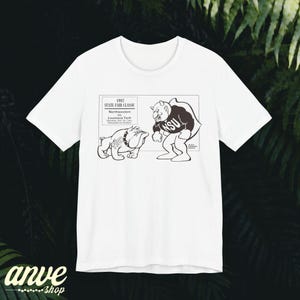 May include: A white short-sleeved t-shirt featuring a black graphic print of a 1987 State Fair Classic football game between Northwestern and Louisiana Tech, depicting a bulldog and a mascot character facing each other in a rectangular frame.