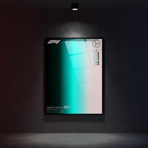 May include: A framed poster with a gradient of teal and white, featuring the Mercedes-AMG Petronas Formula One Team logo and text. The poster is displayed on a dark gray wall, illuminated by a single overhead light.
