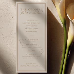 Può includere: Un cartoncino rettangolare per il programma del matrimonio in tonalità beige chiaro con un bordo sottile. Il testo recita THE WEDDING Juliet & Michael, seguito dall'ordine della cerimonia, i nomi del corteo, 18 luglio 2026 e Bald Head Island.