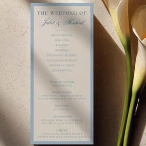 Könnte beinhalten: Eine rechteckige Hochzeitskarten-Programmkarte mit hellblauem Rand und beigem Hintergrund. Der Text lautet: The Wedding of Juliet & Michael, gefolgt vom Ablauf der Zeremonie sowie den Namen der Trauzeugen, Brautjungfern, Groomsmen und Ushers.