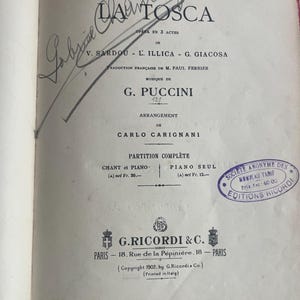 May include: An open book displaying the title "Tosca" by G. Puccini, with text in French and a handwritten signature. Published by G. Ricordi & C., Paris, in 1902. The page includes a stamp and musical notation.