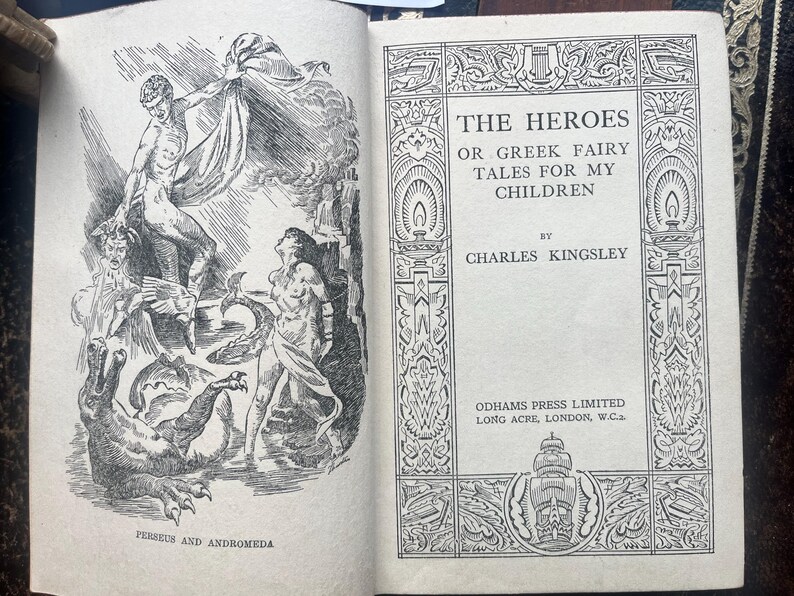 May include: Open book with illustrations and text. The left page features a detailed black and white illustration of Perseus and Andromeda. The right page displays the title "THE HEROES OR GREEK FAIRY TALES FOR MY CHILDREN" by Charles Kingsley.