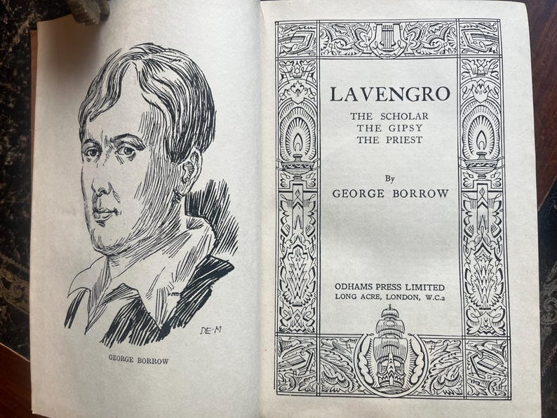 May include: An open book with a black and white illustration of a man on the left page and the title "Lavengro" on the right page. The book's author is George Borrow.