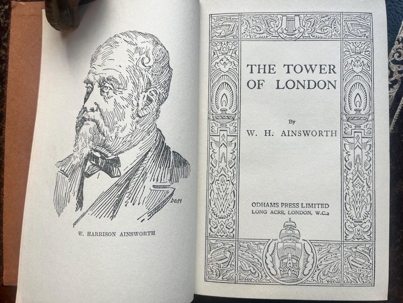 May include: An open book with a black and white illustration of a man with a beard and a bow tie. The book's title is "THE TOWER OF LONDON" by W. H. Ainsworth, published by Odhams Press Limited.