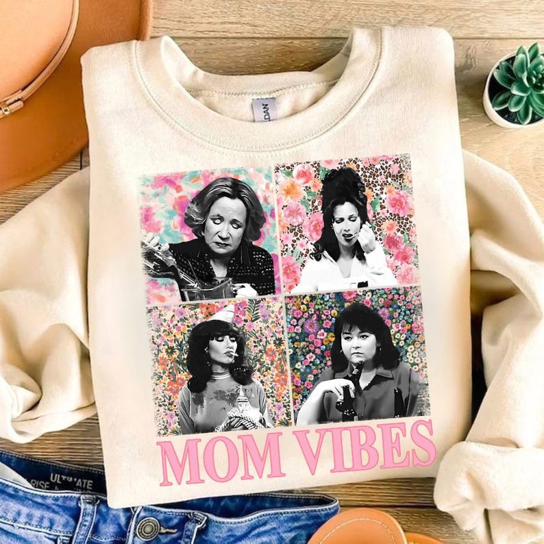 a white t-shirt with a collage of four black and white photographs of women, along with the text "MOM VIBES" printed on it.