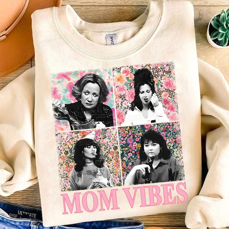 a white sweatshirt with a collage of four black and white photographs of women, along with the text "MOM VIBES" printed on the front.