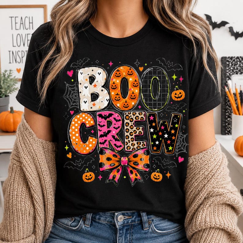 A person wearing a black t-shirt with the text "BOO CREEK" printed on it, surrounded by Halloween-themed decorations such as bats, pumpkins, and a spider web.