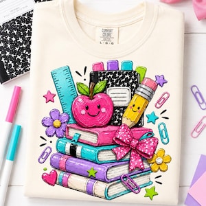 a white t-shirt with a colorful illustration of school supplies, including a pencil, a book, and a flower, along with a smiling apple. The t-shirt is surrounded by various school supplies, such as markers, scissors, and a notebook, creating a playful and educational atmosphere.