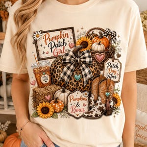 May include: A cream-colored t-shirt featuring a graphic print of pumpkins, sunflowers, a basket, cowboy boots, and a cup of apple cider. The design includes text that reads Pumpkin Patch Girl, Patch Day Vibes, and Pumpkins & Bows with heart accents.